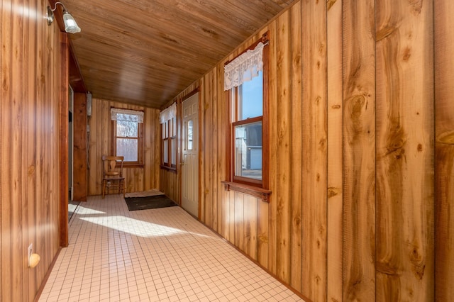 corridor featuring wood ceiling, wooden walls, and light tile patterned flooring