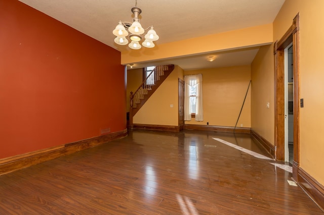 spare room with baseboards, stairway, a chandelier, and wood finished floors