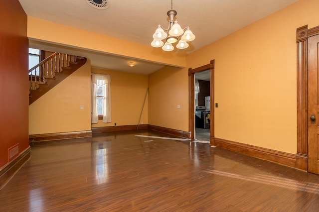 unfurnished room with baseboards, visible vents, wood finished floors, an inviting chandelier, and stairs