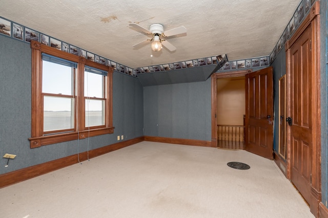 unfurnished room with a textured ceiling, ceiling fan, baseboards, and light colored carpet