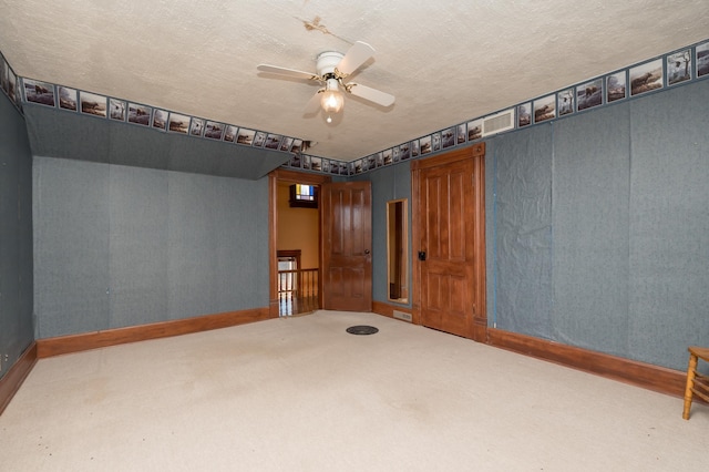 spare room with baseboards, visible vents, a ceiling fan, carpet, and a textured ceiling