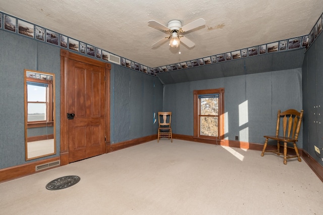 living area with a textured ceiling, visible vents, baseboards, a ceiling fan, and carpet