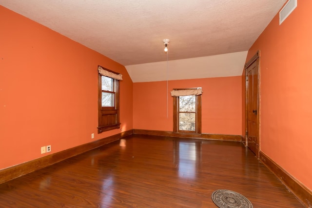 spare room with lofted ceiling, plenty of natural light, baseboards, and wood finished floors