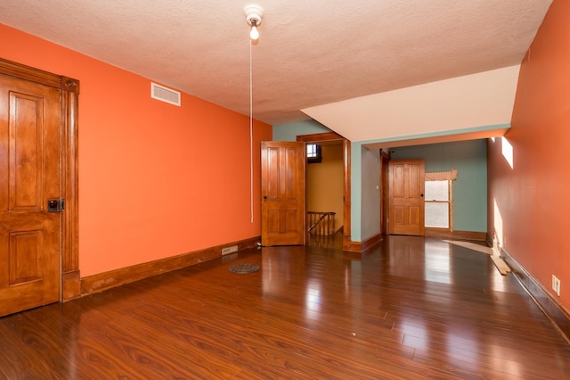 spare room with visible vents, a textured ceiling, baseboards, and wood finished floors