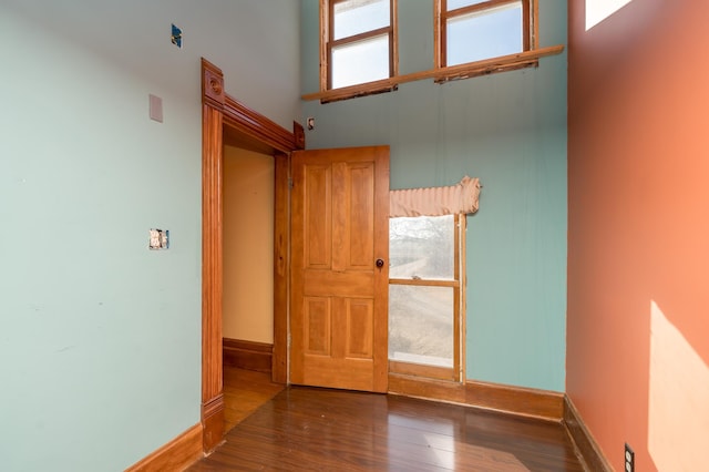 spare room featuring a high ceiling, baseboards, and wood finished floors