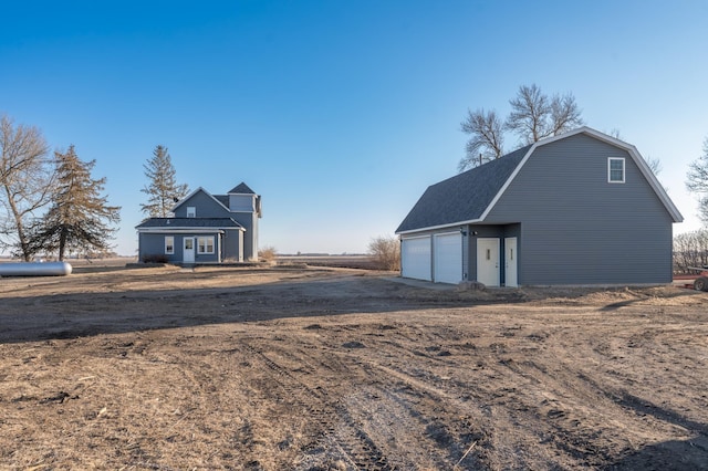 exterior space featuring a garage, an outdoor structure, and a gambrel roof