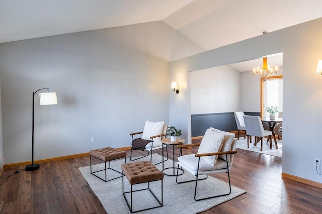 living area featuring lofted ceiling, baseboards, a notable chandelier, and hardwood / wood-style floors