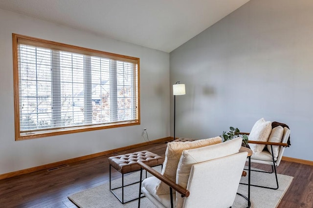 living area featuring vaulted ceiling, wood finished floors, visible vents, and baseboards