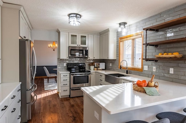 kitchen featuring a peninsula, appliances with stainless steel finishes, light countertops, and a sink