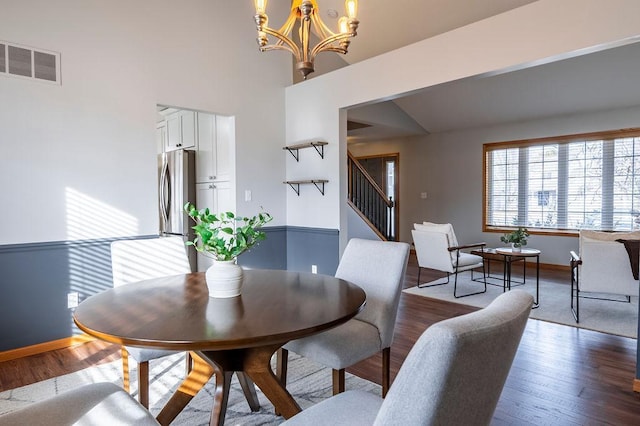 dining space with baseboards, visible vents, dark wood finished floors, stairway, and an inviting chandelier