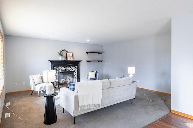 living area featuring visible vents, baseboards, wood finished floors, and a tile fireplace