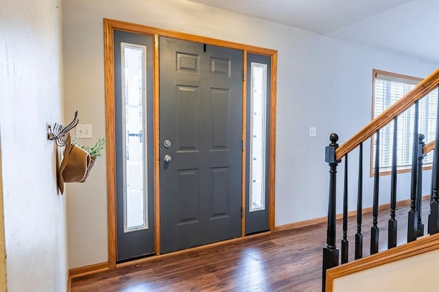 foyer entrance with stairs, baseboards, and wood finished floors