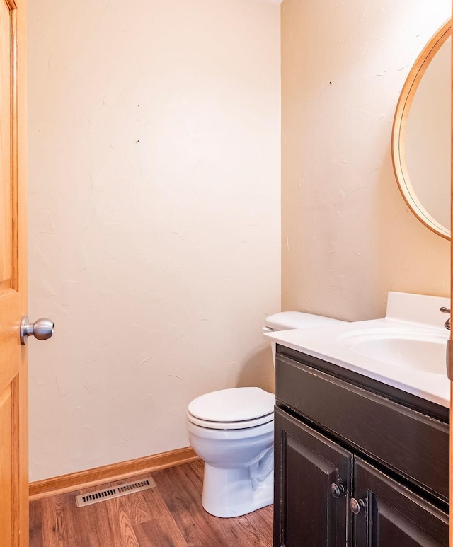 bathroom with baseboards, visible vents, toilet, wood finished floors, and vanity