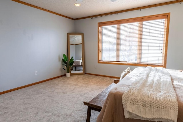 carpeted bedroom with a textured ceiling, ornamental molding, and baseboards