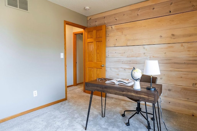 carpeted office featuring baseboards, wooden walls, and visible vents