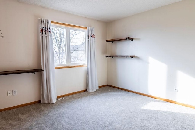 unfurnished room featuring baseboards, a textured ceiling, and light colored carpet