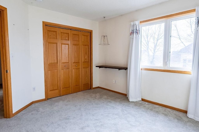 unfurnished bedroom featuring a closet, carpet, visible vents, and baseboards