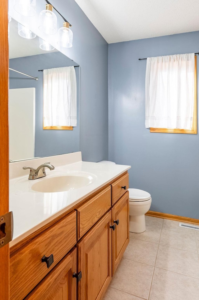 bathroom featuring visible vents, toilet, vanity, tile patterned flooring, and baseboards