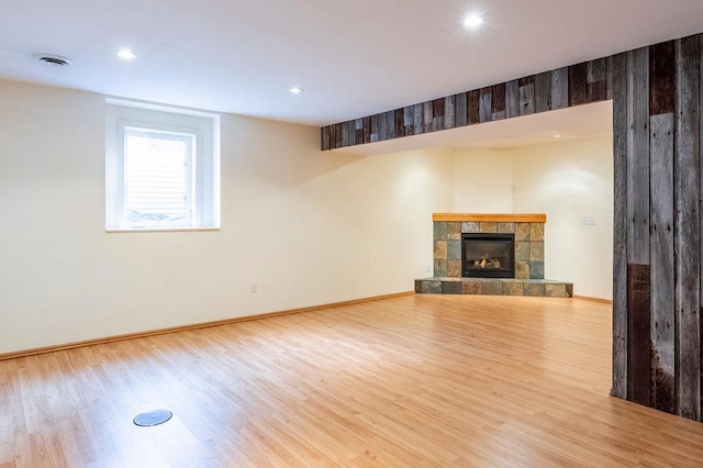 unfurnished living room with baseboards, visible vents, a tiled fireplace, wood finished floors, and recessed lighting