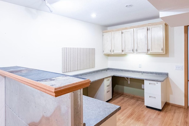 unfurnished office featuring light wood-style flooring, baseboards, built in desk, and recessed lighting