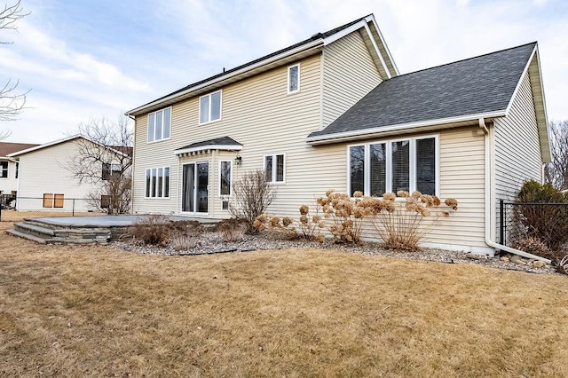 rear view of property featuring roof with shingles, a lawn, a patio area, and fence