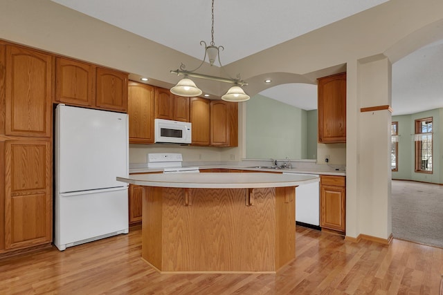 kitchen featuring white appliances, a kitchen bar, a kitchen island, and light countertops