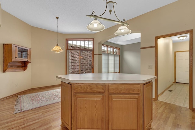 kitchen featuring light countertops, light wood finished floors, and decorative light fixtures