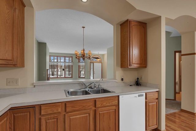 kitchen featuring a sink, brown cabinets, light countertops, and dishwasher