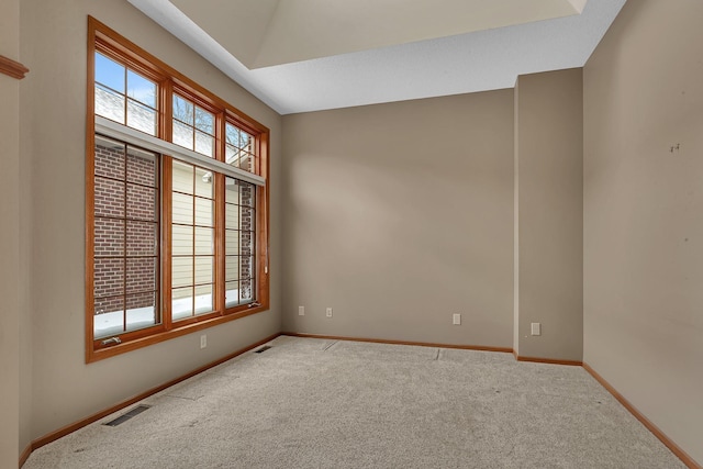 carpeted spare room featuring baseboards, vaulted ceiling, visible vents, and a healthy amount of sunlight