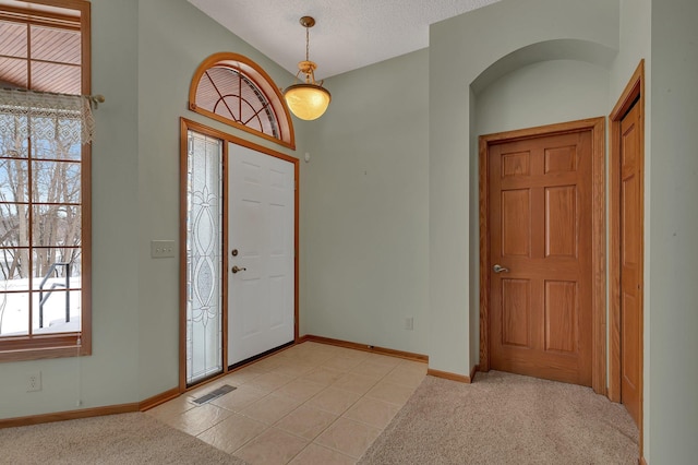 entryway featuring baseboards, visible vents, a textured ceiling, and light colored carpet