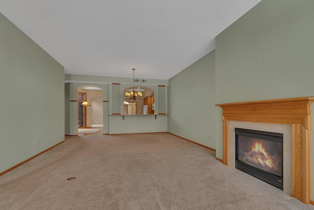 unfurnished living room featuring carpet floors, a premium fireplace, baseboards, and a notable chandelier