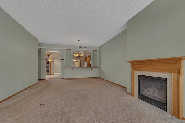 unfurnished living room featuring carpet floors, a notable chandelier, baseboards, and a premium fireplace