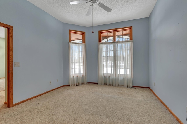 carpeted empty room featuring a ceiling fan, a textured ceiling, and baseboards