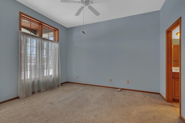 carpeted empty room with a ceiling fan, baseboards, and a textured ceiling