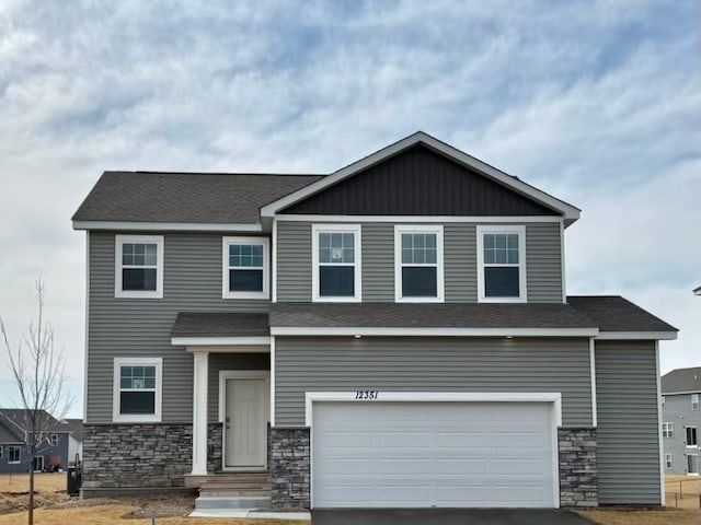 craftsman-style house with aphalt driveway, stone siding, roof with shingles, and an attached garage