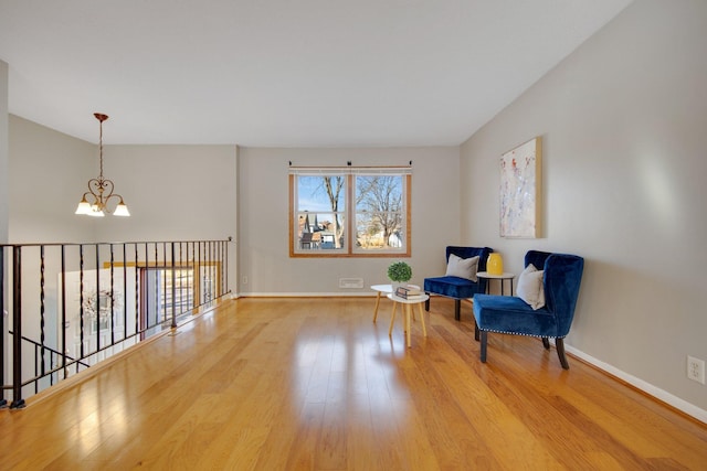 sitting room featuring baseboards, an inviting chandelier, and wood finished floors