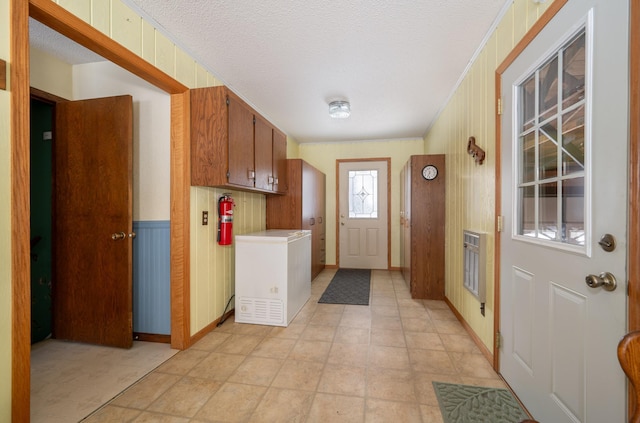 interior space featuring wooden walls, crown molding, and a textured ceiling