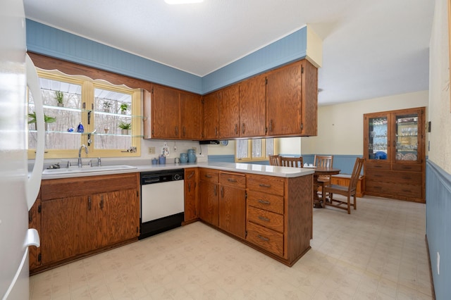 kitchen featuring a wainscoted wall, light floors, white appliances, and a sink