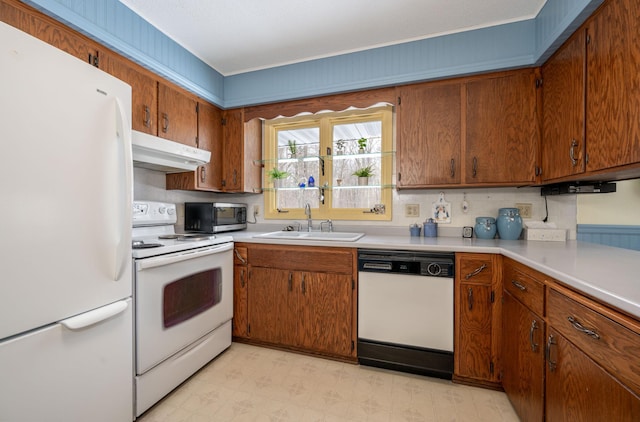 kitchen with white appliances, a sink, under cabinet range hood, and light floors