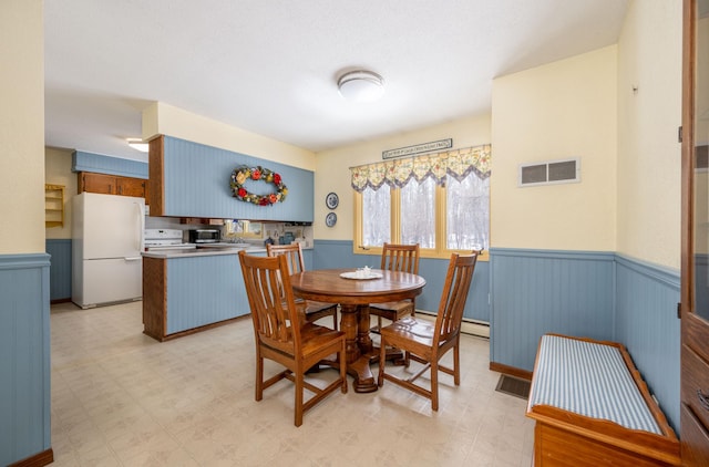 dining space with wainscoting, visible vents, and light floors