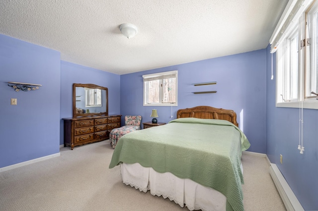 bedroom with a baseboard heating unit, a textured ceiling, carpet flooring, and baseboards