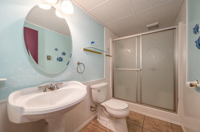 full bathroom with a stall shower, tile patterned flooring, a drop ceiling, and toilet