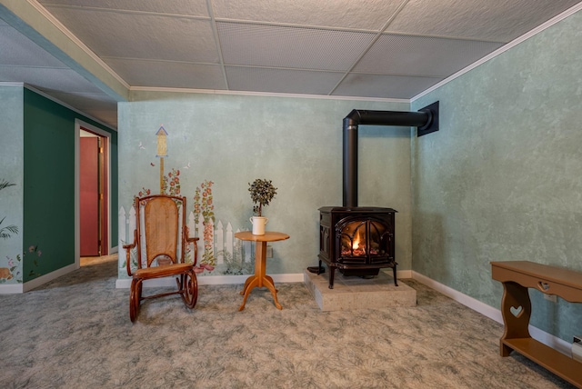 sitting room with carpet floors, a wood stove, baseboards, and ornamental molding