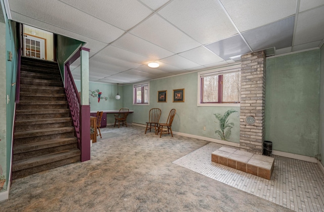 below grade area with carpet floors, a drop ceiling, baseboards, and stairs