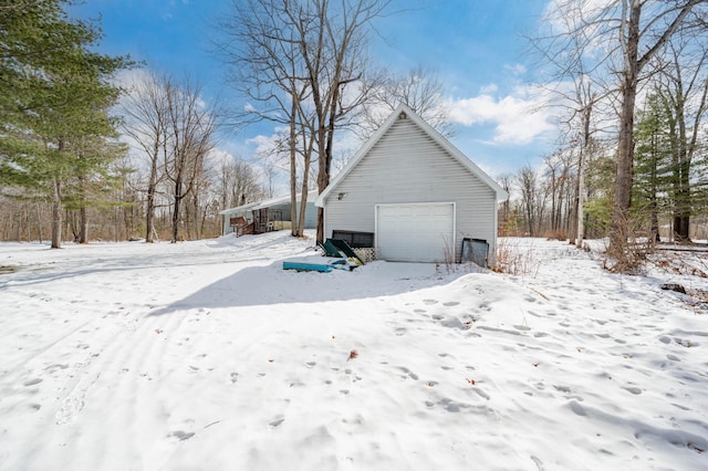 view of snowy exterior with a garage and an outbuilding