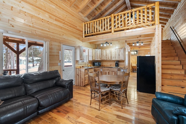 dining area featuring high vaulted ceiling, light wood-type flooring, wood ceiling, and wood walls