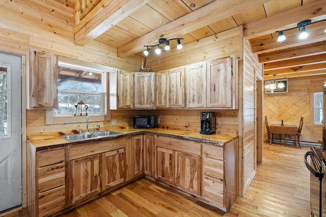 kitchen featuring beamed ceiling, light wood-style flooring, black appliances, a sink, and wooden walls