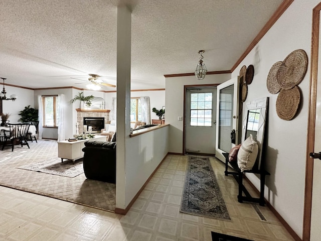 foyer with ceiling fan with notable chandelier, ornamental molding, a fireplace, and baseboards