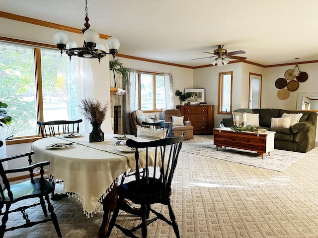 dining room featuring a fireplace, baseboards, crown molding, and ceiling fan with notable chandelier