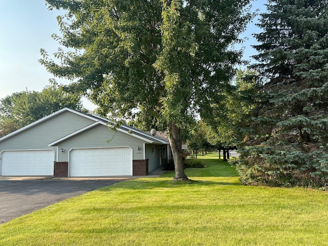 view of front of home featuring a garage, brick siding, a front lawn, and aphalt driveway